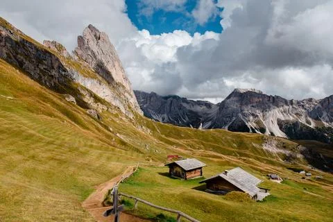 Seceda mountain range with traditional alpine huts and dramatic cloudy sky Stock Photos