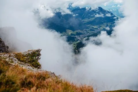 Seceda mountain ridge with clouds and a village nestled in the valley below Stock Photos