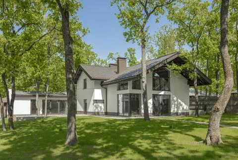 Secluded modern luxury two-storey house in the forest. Country house with lawn Stock Photos