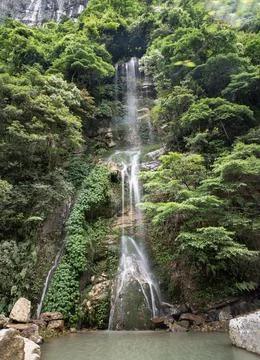 A secluded plunge pool catching a multi-tiered waterfall, surrounded by anc.. Foto stock