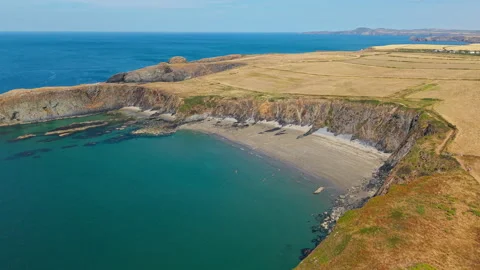 Secluded Sandy Cove Below Rugged Cliffs on Pembrokeshire Coast, Drone Push In 스톡 동영상 345504239