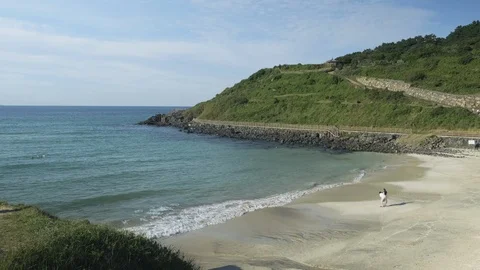 Secluded small beach with gentle waves. Lovers watching the sea. Jeju Island, So Stock Footage 117694343