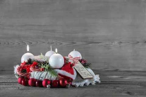 Second advent: two burning candles decorated in white and red on wood. Stock Photos