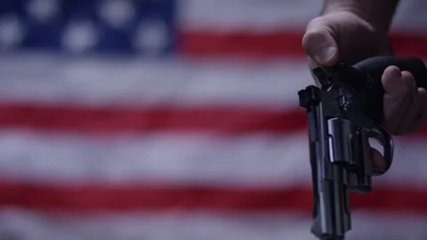 Second Amendment - American gun rights holding pistol in front of flag Stock Footage 300899798