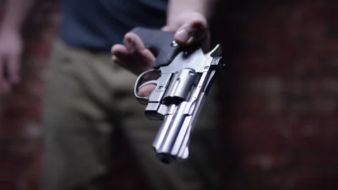 Second Amendment - Man hands over his firearm weapon revolver Stock Footage 301089102