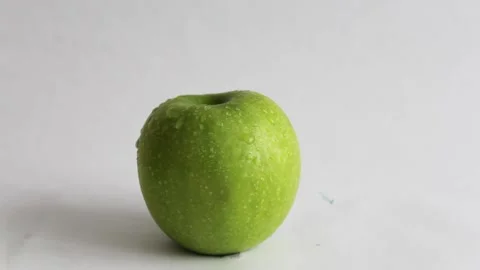 A second apple on a white background rolls up to a green apple in drops of water Stock Footage 243022627