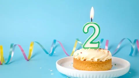 Second Birthday Celebration: Cake with Number Two Candle on Blue Background Stock Footage 333410374