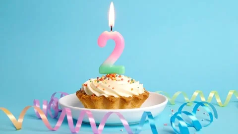 Second Birthday Celebration: Cupcake with Number Two Candle and Colorful Sp.. Stock Footage 333410378