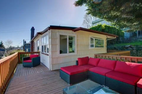 Second floor deck features wicker outdoor sofa with red cushions. Stock Photos