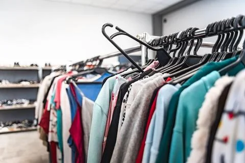 Secondhand clothing rack packed with assorted sweaters, jackets, and tops i.. 写真素材