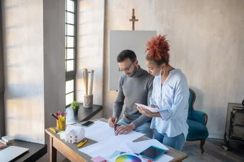 Secretary making notes about schedule of interior designer Stock Photos