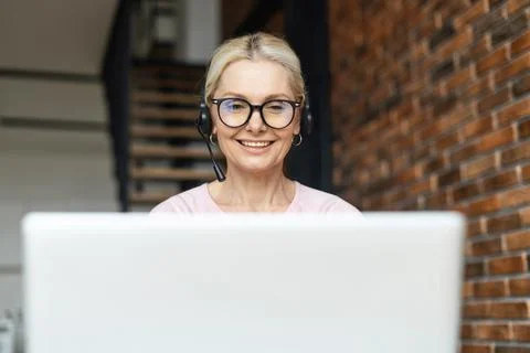 Secretary sitting in front of computer with headset and looking at the monitor Stock Photos