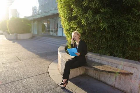 Secretary talking by smartphone with document case in   outdoors Stock Photos