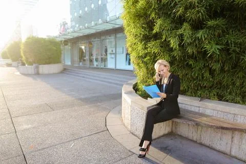 Secretary talking by smartphone with document case in   outdoors Stock Photos