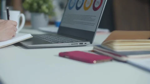 The secretary writes a note and works with the laptop Stock Footage 129979504