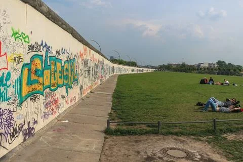 A section of the Berlin Wall covered with graffiti. On the right, people ar.. Stock Photos