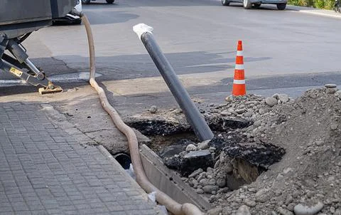 A section of a city road, at the edge of which a pipeline made of a plastic p 库存照片