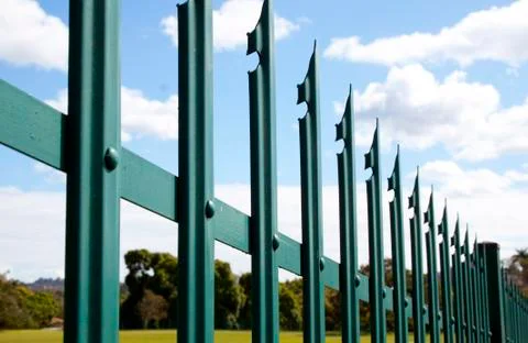 Section closeup of green palisade security fence against blue sky Stock Photos