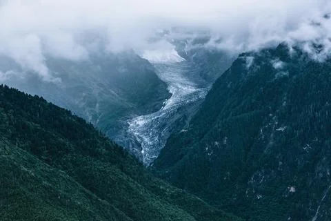 A section of glacier under the clouds between high mountains Stock Photos
