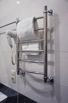 A section of a light-tiled bathroom. A stainless steel heated towel rail ha.. Фото