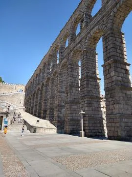 Section of a massive ancient stone aqueduct towering over a plaza Stock Photos