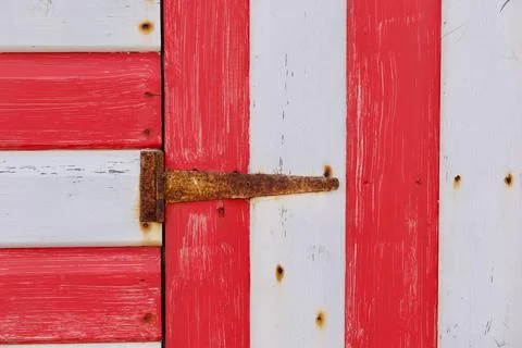 Section of red and white painted wooden hut with rusty hinge Stock Photos