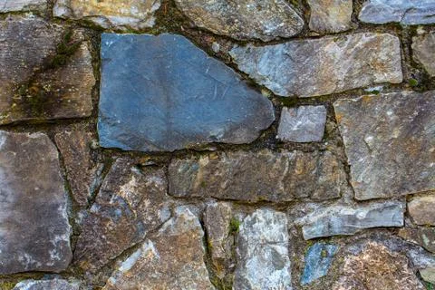 A section of a stone wall with a big blue stone in front 스톡 사진