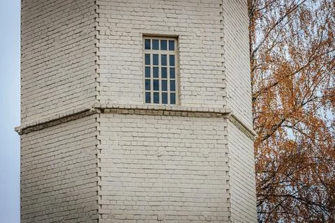 A section of a white brick tower with a small grid window Stock Photos