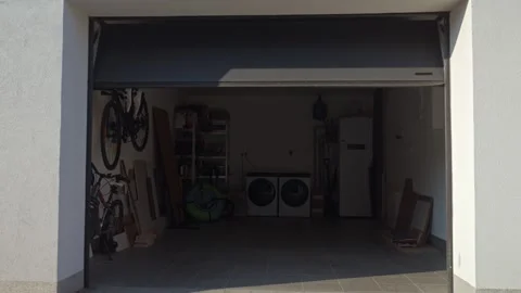 Sectional garage door is closing while a hand holds remote control outside Stock Footage 333598750