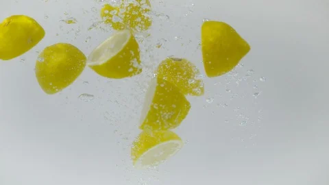 Sectioned lemons being dropped into water, Ultra Slow Motion Video stock 86583233