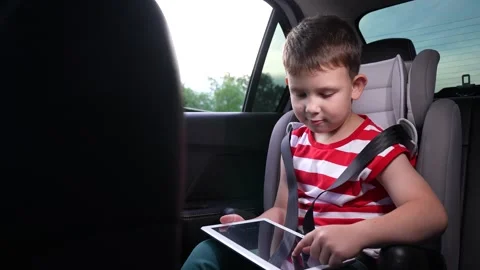 Secure journey for kid, Relaxed boy in car, Enjoying tablet activities, Learning Stock Footage 314289590