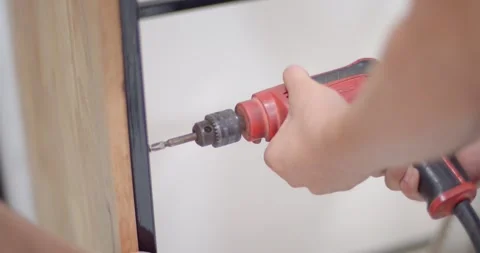 Secure the nut between the steel and the wood using a small drill. Stock Footage 222620861