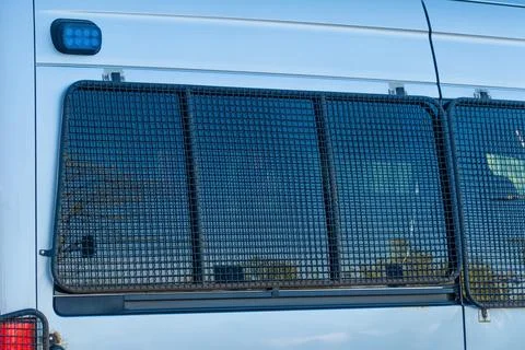 Secure police van window with protective mesh guard and blue light attachment Stock Photos
