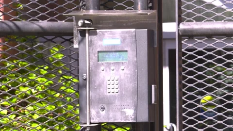 Secure Stainless Steel Intercom Keypad Mounted on Wire Mesh Gate Stock Footage 347813390