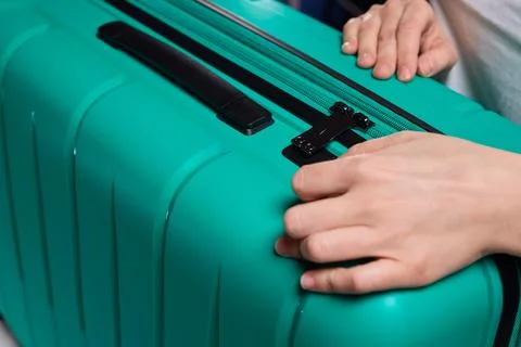 Secure suitcase with combo lock, Hands set combination on teal suitcase with Stock Photos