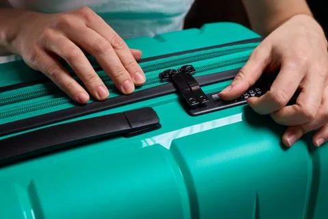 Secure suitcase with combo lock, Hands set combination on teal suitcase with Stock Photos