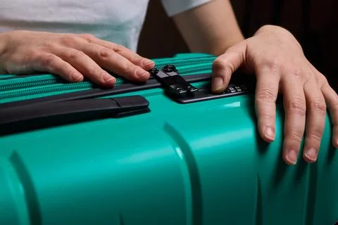 Secure suitcase with combo lock, Hands set combination on teal suitcase with Stock Photos
