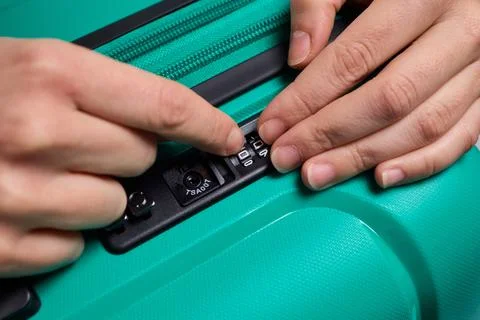 Secure suitcase with combo lock, Hands set combination on teal suitcase with Stock Photos