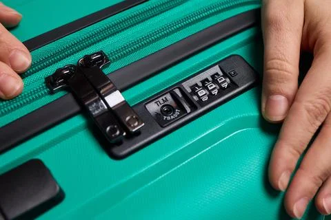 Secure suitcase with combo lock, Hands set combination on teal suitcase with Stock Photos