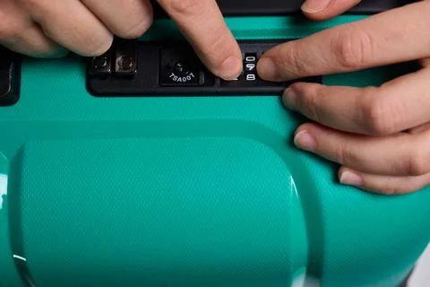 Secure suitcase with combo lock, Hands set combination on teal suitcase with Stock Photos