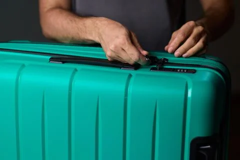 Secure suitcase with combo lock, Hands set combination on teal suitcase with Stock Photos