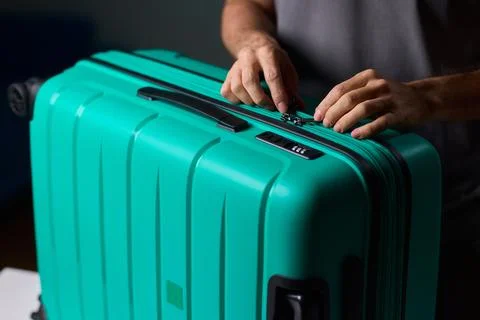 Secure suitcase with combo lock, Hands set combination on teal suitcase with Stock Photos