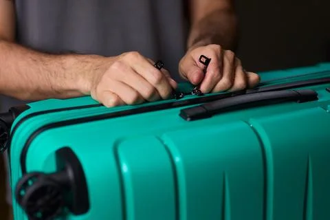 Secure suitcase with combo lock, Hands set combination on teal suitcase with Stock Photos