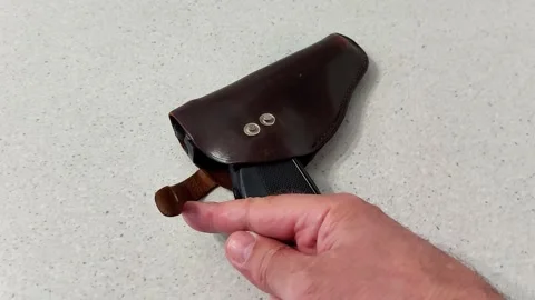Securing a Black Pistol in Brown Leather Holster with Snap Closure Vídeo Stock 321859270