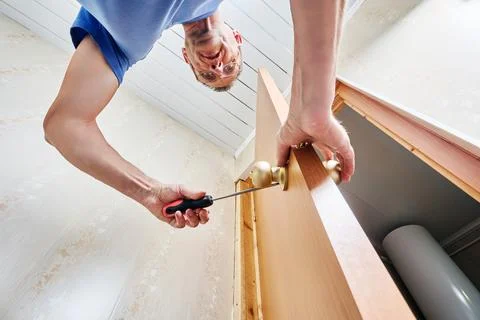 Securing door knobs by tightening screws with screwdriver to fix handles fi.. Stock Photos