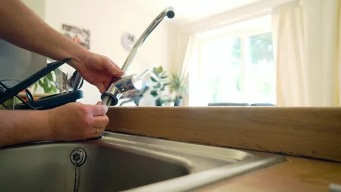Securing flexible water lines into new kitchen faucet, hand assembling plumbing Vidéo 338069432