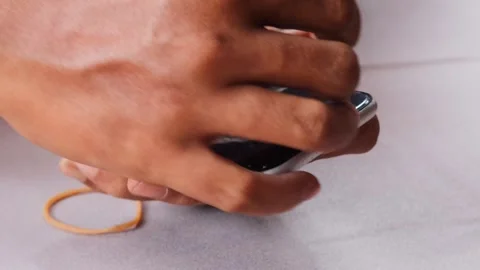 Securing a slightly lifted smartphone screen with a rubber band Stock Footage 345103494