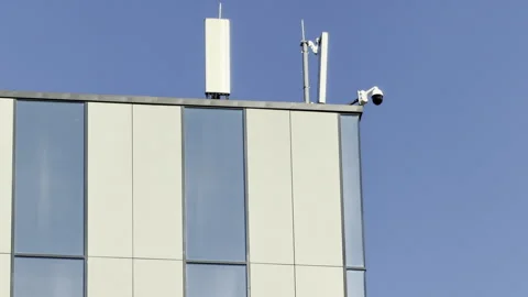 Security camera and antennas overlook the city from a modern building roof Stock Footage 336937099