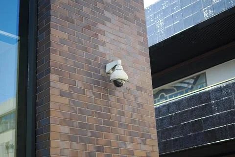Security camera on a brick wall in an urban area Stock Photos