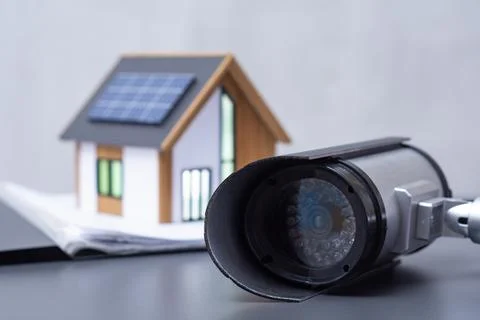 A security camera CCTV with miniature smart home model featuring solar pane.. Stock Photos